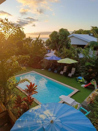 an outdoor swimming pool with umbrellas and chairs and a pool at Résidence Amarosa in Les Avirons