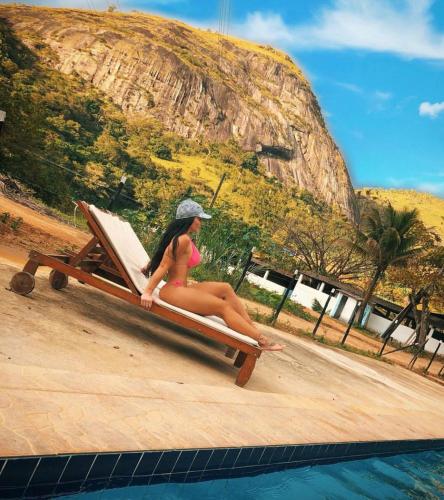 a woman sitting on a beach chair next to a pool at FLAT 228 - Hotel Pedra do Rodeadouro-Bonito-PE in Bonito