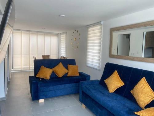 ein blaues Sofa mit goldenen Kissen im Wohnzimmer in der Unterkunft Casa Familiar Excelente ubicación con Piscina in La Tebaida