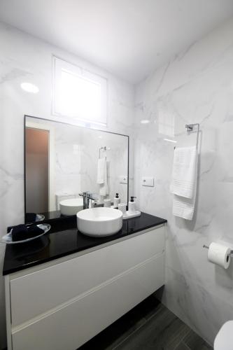 a white bathroom with a sink and a mirror at Venecia in A Pobra do Caramiñal