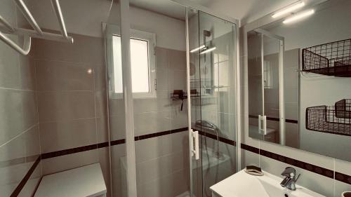 une salle de bain avec une douche, un lavabo et un miroir dans l'établissement Les océanides, T2 face océan, à Notre-Dame-de-Monts