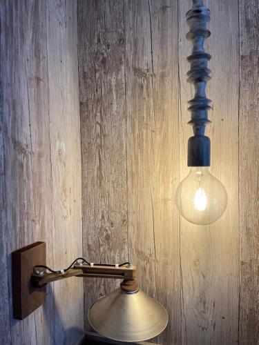 a lamp with a light on a wooden wall at 1957 To Rodo kai to Roido in Karpenision