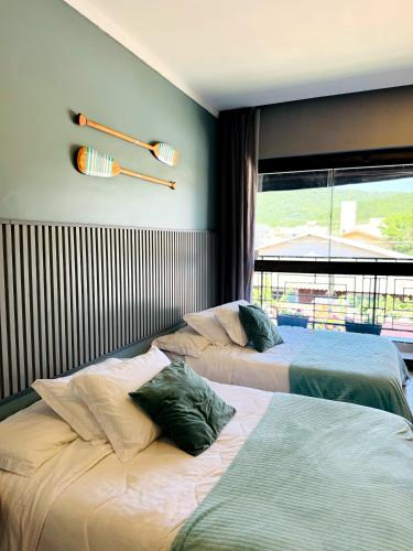 two beds sitting in a room with a window at Pousada Doce Lar in Penha