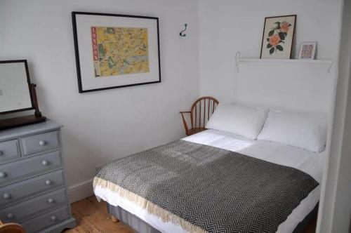 een kleine slaapkamer met een bed en een dressoir bij Lovely fisherman's cottage near beach and harbour in Whitstable