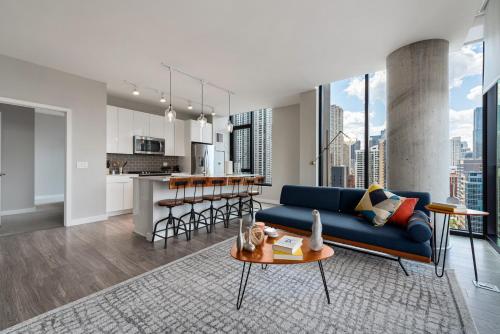 a living room with a blue couch and a kitchen at Aurelien Spacious Apartments in the Heart of Gold Coast in Chicago