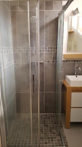 een douche met een glazen deur in de badkamer bij Petite maison bord de plage in Les Pieux