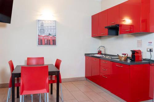 a kitchen with red cabinets and a table with red chairs at Easy Space in Bientina
