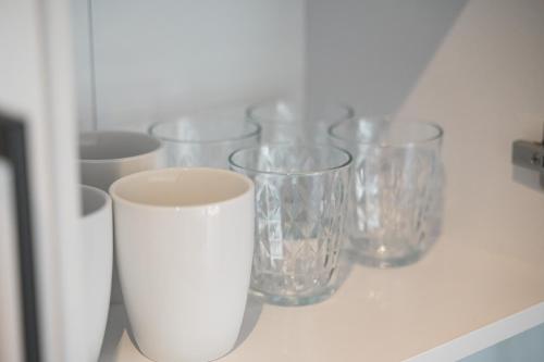 a row of clear glasses sitting on a shelf at Roomfall Apartment am Kurpark mit TG & Wifi & Balkon in Bad Rappenau