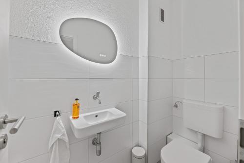 a white bathroom with a sink and a mirror at ☆Roomfall: Design Suite am Kurpark in Bad Rappenau