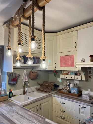 a kitchen with white cabinets and a sink and lights at 1957 To Rodo kai to Roido in Karpenisi