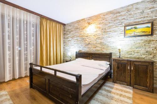 ein Schlafzimmer mit einem Bett und einer Ziegelwand in der Unterkunft Hanul Simon in Bran
