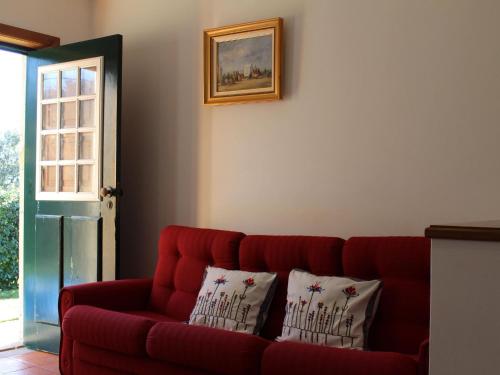 czerwona kanapa w salonie z dwoma poduszkami w obiekcie Beautiful cottage on the estate of a farm w mieście Ponte de Lima