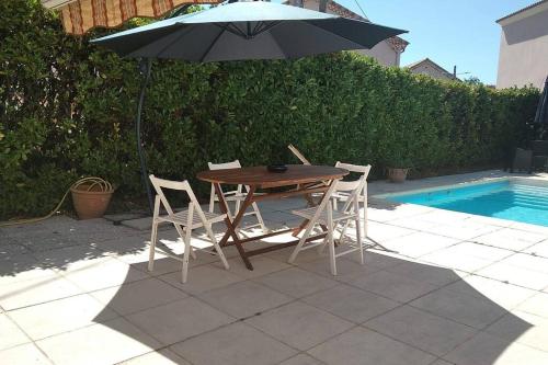 une table et des chaises avec un parasol à côté d'une piscine dans l'établissement Grande Villa Ardèche, à Le Teil