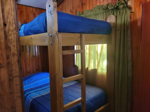 dwa łóżka piętrowe w kabinie z niebieską pościelą w obiekcie Cabañas Buen Recuerdo w mieście Puyehue
