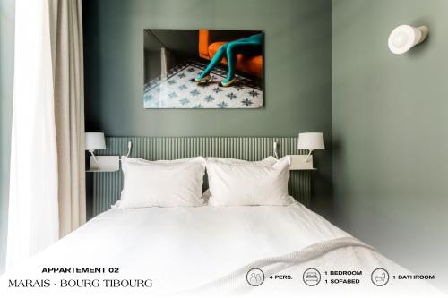 パリにあるBeauquartier - Marais, Bourg Tibourgのベッドと壁に絵が飾られた寝室