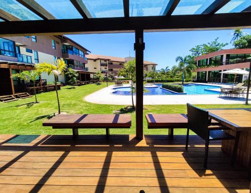 a patio with two benches and a swimming pool at Reserva dos Carneiros - Flat-Apartamento em Carneiros in Tamandaré