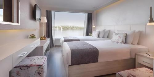 a hotel room with two beds and a large window at NILE CRUISE LUXOR & ASWAN A in Luxor