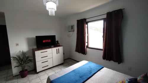 um quarto com uma cama, uma televisão e uma janela em Mandallah Hostel em Joinville