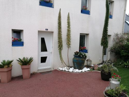 a white building with potted plants and a door at Ty Pempoul - logement 2 chambres - 100 m de la plage in Saint-Pol-de-Léon