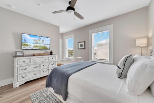 a bedroom with a white bed and a flat screen tv at Newly Built, Luxury Home w/ pool & beach access in Gulf Shores