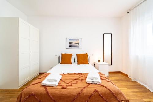 a white bedroom with a large bed with orange pillows at Flat Armada II - Apartamento T5 junto ao BragaParque in Braga