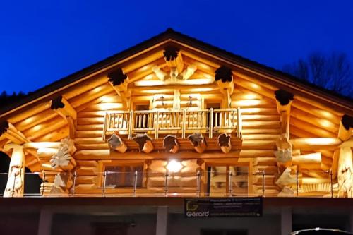 a log cabin with a balcony at night at Chalet 10 pers sauna & SPA La tanière des Vosges in La Bresse