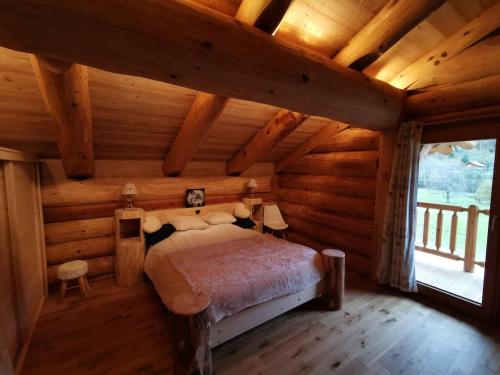 une chambre avec un lit dans une cabane en rondins dans l'établissement Chalet 10 pers sauna & SPA La tanière des Vosges, à La Bresse