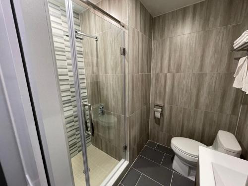 uma casa de banho com um WC e uma cabina de duche em vidro. em King Hotel Brooklyn Sunset Park em Brooklyn