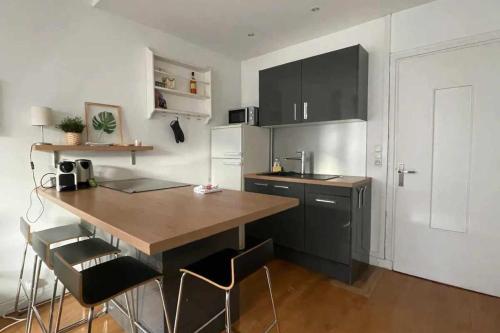 kuchnia z drewnianym stołem i czarnymi szafkami w obiekcie 41m love nest for a pleasant stay in Lyon w mieście Lyon