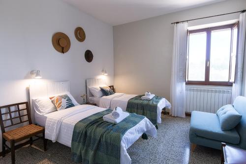 una habitación de hotel con 2 camas y una silla en ZEM casolare en Petriolo