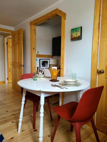 una sala da pranzo con un tavolo bianco e sedie rosse di La Petite Auberge Sur Queen a Rawdon