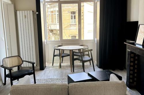 a living room with a table and chairs and a window at Au Cabinet Childeric in Tournai