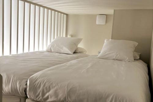 a white bed with two pillows sitting next to a window at Au Cabinet Childeric in Tournai