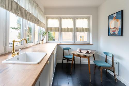 a kitchen with a sink and a table with chairs at Apartament VinyLove - blisko Parku Zdrojowego i Term - by Space Apart in Jelenia Góra