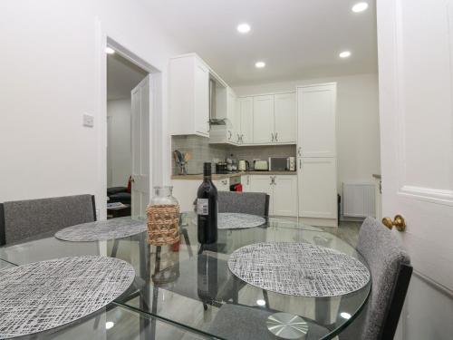 a glass table with a bottle of wine and two chairs at RockStar Cottage in Macduff