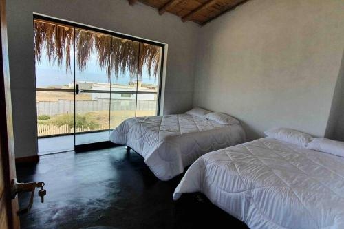 2 camas en una habitación con ventana grande en Casa de Playa con Piscina Privada, en Los Órganos