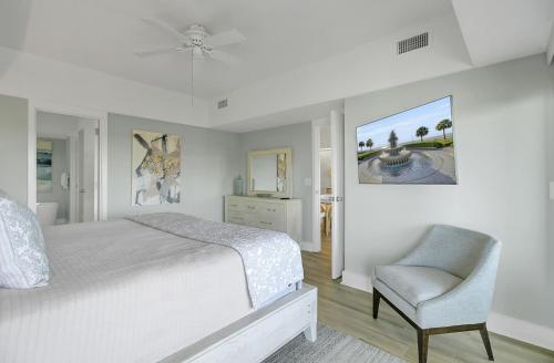 a white bedroom with a bed and a chair at 1408 Ocean Club by AvantStay Oceanfront Home w Amazing Views in Isle of Palms