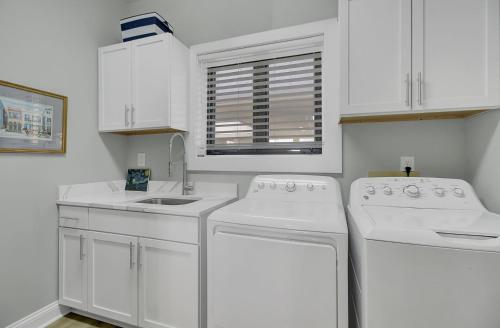 a white kitchen with white appliances and a window at 1408 Ocean Club by AvantStay Oceanfront Home w Amazing Views in Isle of Palms