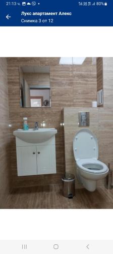 La salle de bains est pourvue de toilettes blanches et d'un lavabo. dans l'établissement Лукс апартамент Алекс, à Blagoevgrad