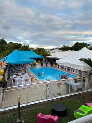 a large swimming pool with tables and chairs and umbrellas at Les Villas de Boisvin in Le Moule