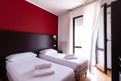 2 letti in una camera con parete rossa di Hotel Guidi a Mestre