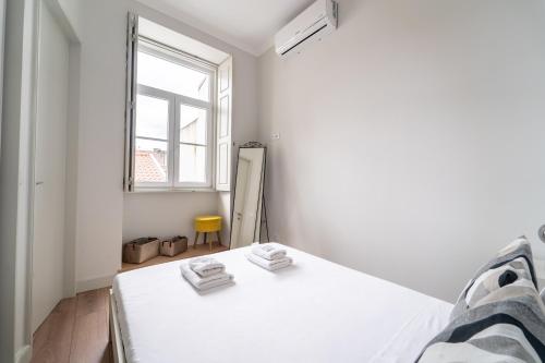 a white bedroom with a bed and a window at Escadaria 21 Apartment by House and People in Braga