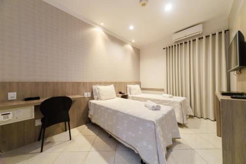 a hotel room with two beds and a television at Realce Hotel in Jaú