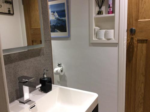 Un baño con un lavabo blanco y un espejo. en Hardy Croft Hideaway, en Grassington