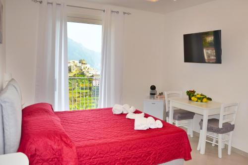 um quarto com uma cama vermelha com uma mesa e uma janela em Amalfi Montemare Rooms em Amalfi
