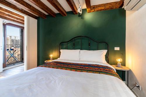 a bedroom with a white bed with a green wall at Ca' dell'Arciere Apartments in Venice