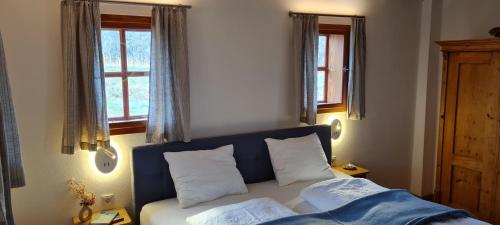 uma cama num quarto com duas janelas e uma cama com almofadas em Luxuriöses Landhaus Kaag 1723 