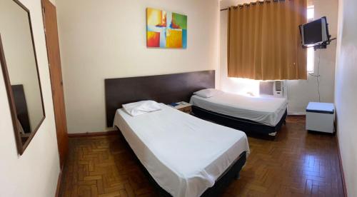 a hotel room with two beds and a tv at HOTEL TRES LAGOAS in Três Lagoas