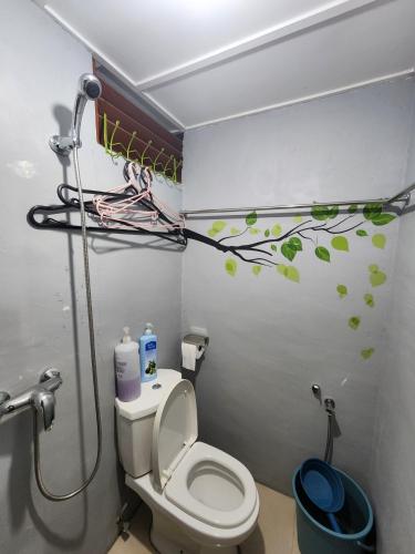 a bathroom with a toilet and a shower with green leaves on the wall at Rock Forest Chalet in Bentong