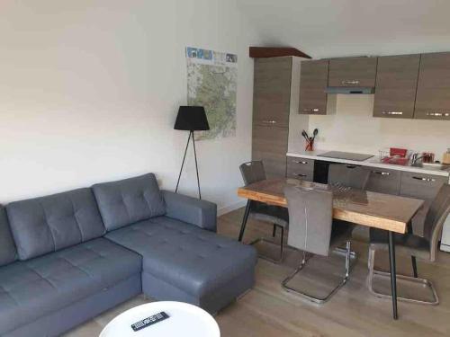 un salon avec un canapé et une table et une cuisine dans l'établissement Gîte au bord du loing et proche forêt, à Écuelles